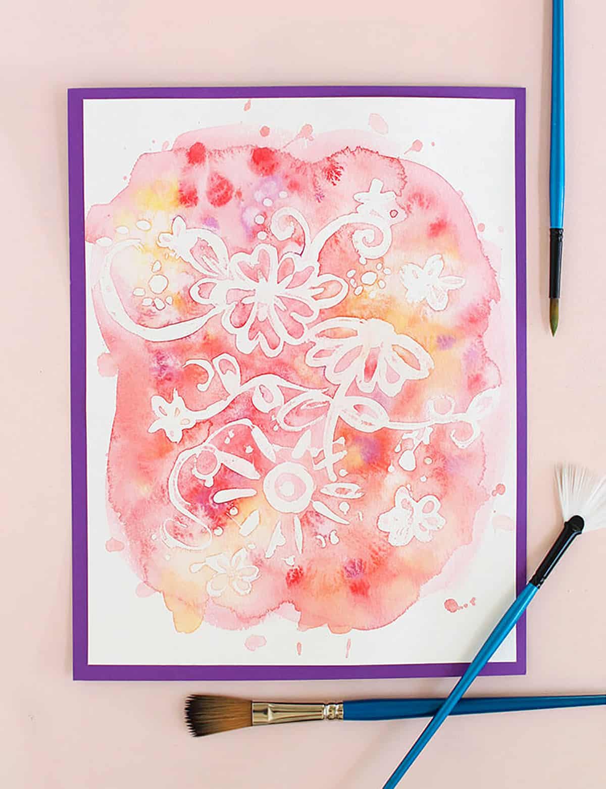 rubber cement watercolor resist art surrounded by paint brushes
