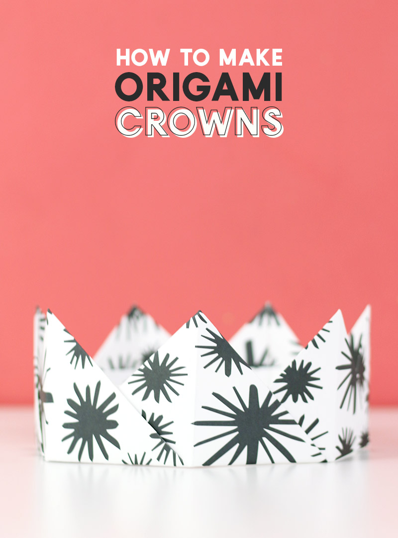 white and blue patterned origami crown sitting in front of pink background