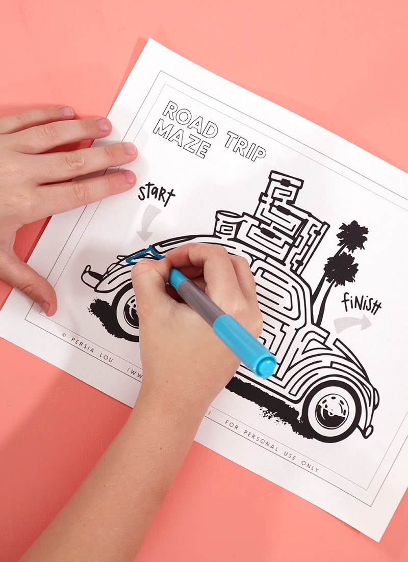 kids hands drawing in free printable road trip themed maze activity