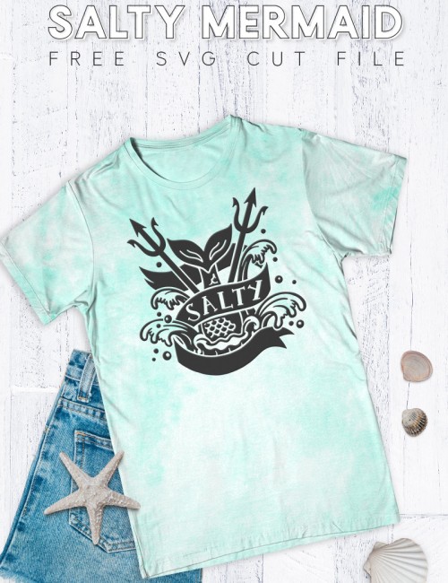 Mint green tie dye t-shirt with black design on the front in a tattoo style of a mermaid tail splashing into the water. The banner around the mermaid tail reads, "Salty."