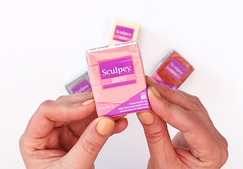 Hands holding Sculpey Souffle Oven Bake Clay in French Pink over a white background