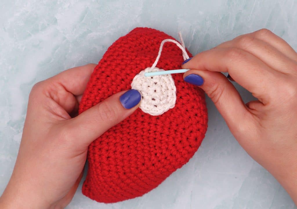 sewing on mushroom spots to crochet mushroom bag